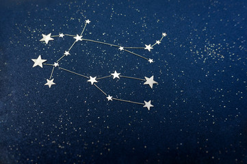 Gemini zodiac sign on the starry sky close up. Application from star confetti and glitter black...
