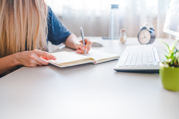 Fototapeta premium girl writes in a notebook, draws up a schedule for the week