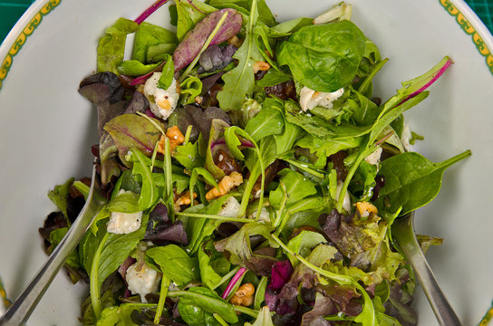 Recipiente con una ensalada de lechuga, tomate, d&aacute;tiles y nueces