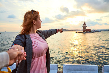 Follow me. A woman tourist leads her friend to the Maiden Tower (Kiz Kulesi in Turkish) also known as Leander's tower, symbol of Istanbul, Turkey