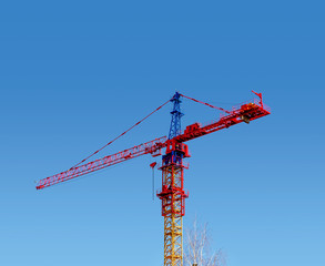 Tower crane red color on a blue sky background. Construction, industry, city development