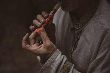 A man in a Russian national costume blows a handmade whistle.
