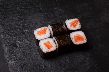 Close-up of maki sushi rolls with salmon on black background
