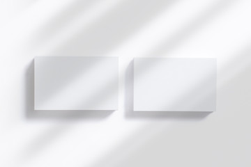 Top view of 2 horizontal business card stacks with shadow overlay from above on white background as template for design presentation, branding, promotion etc.