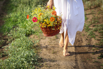 the girl goes and carries a wooden basket with wild flowers.