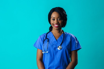 Portrait of a smiling female doctor or nurse wearing blue scrubs uniform and stethoscope, isolated on blue background