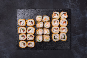 Sushi set with various kinds of hot rolls on a black background