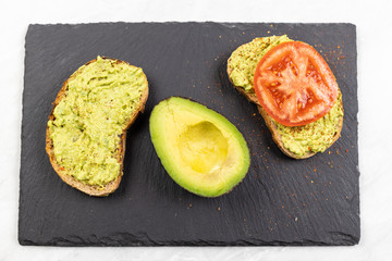 Avocado spread with grated chilly peppers and sliced tomato on the sliced toasted bread