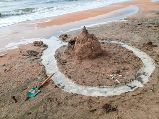 Sand castle on the beach with shells. Childrens games at sea.