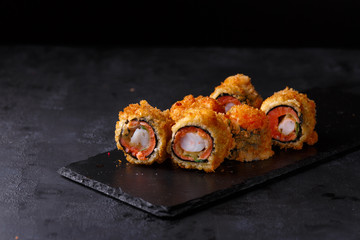 Sushi rolls with salmon, cucumber, parmesan, shrimp on a black background.