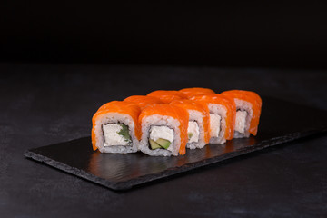 Philadelphia roll sushi with salmon on a black background.