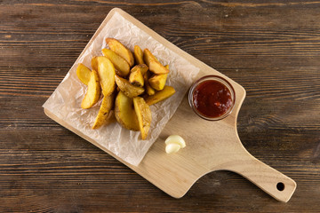 rustic potato with tomato ketchup and garlic on wooden board top view