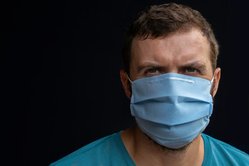 Worried young doctor or nurse man wearing medical face mask, studio portrait. Man wearing face mask during coronavirus outbreak. Virus spread flu prevention quarantine