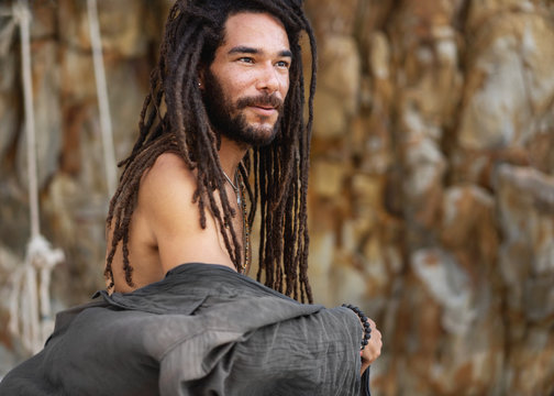 fashion guy with dreadlocks in tropical coconut palms smiling