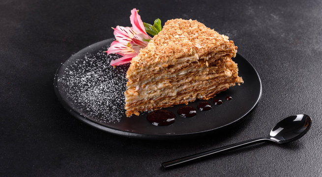 Fresh delicious cake napoleon with cream on a dark background