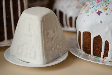 Traditional Russian and Ukrainian Easter cottage cheese dessert in rustic style. Orthodox Paskha in ceramic plate on table with kulich cakes. Still life with curd pyramid and sweet bread in spring day