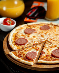 pizza with sliced sausages and orange juice