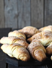 Croissants sprinkled with sesame and sugar on a dark wooden background.Homemade cake.