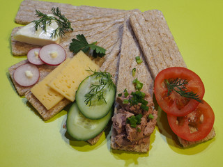 Different sandwiches with rye bread crackers, slices of cheese, cream cheese, tomatoes, cucumbers, radishes, spicy herbs on a bright background. Tasty snacks for healthy and proper nutrition, top view
