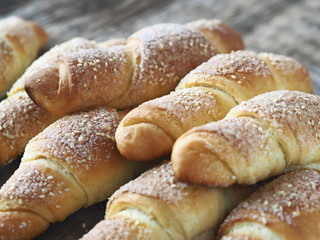 Croissants sprinkled with sesame and sugar on an ancient wooden background.Homemade cake.