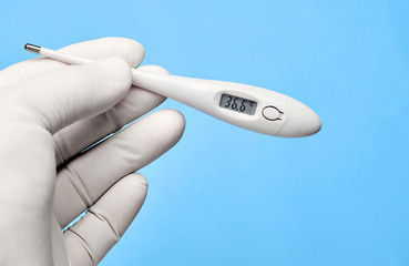 Medical thermometer in hands on a blue background.