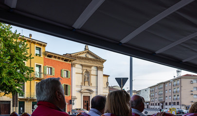 Tourists ride at dusk a double-decker tourist bus and see the sights in the old part of Verona city, Italy.