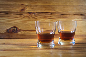 Two glasses of whiskey on a wooden table.
