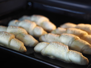 Croissants, sprinkled with sesame and sugar on a baking sheet in the kitchen oven, are ready to be baked.Homemade cake.