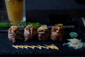 seared salmon and eel sushi rolls on dark background