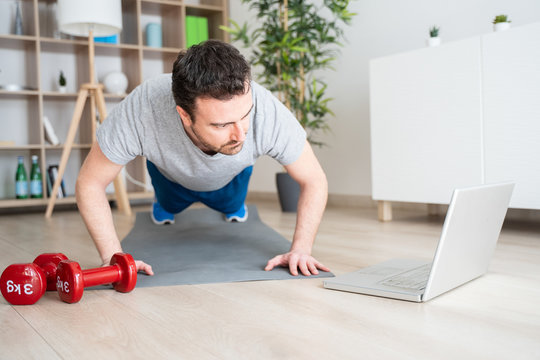 Man doing exercise while watching tutorial on laptop at home