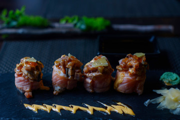 seared salmon and eel sushi rolls on dark background