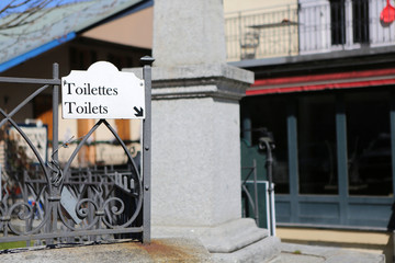 Panneau sur une grille en métal mentionnant les toilettes communales en anglais et en français. Saint-Gervais-les-Bains. Haute-Savoie. France.