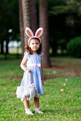 Little toddler girl with bunny ears. Easter egg hunt. - 337055760