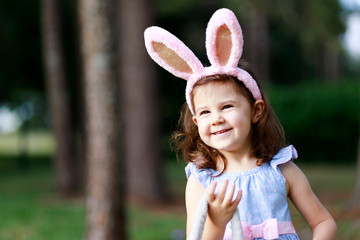 Little toddler girl with bunny ears. Easter egg hunt. - 337055796