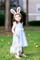 Little toddler girl with bunny ears. Easter egg hunt. - 337055968