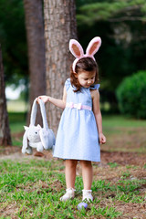 Little toddler girl with bunny ears. Easter egg hunt. - 337055983