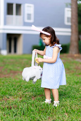 Little toddler girl with bunny ears. Easter egg hunt. - 337056146