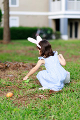 Little toddler girl with bunny ears. Easter egg hunt. - 337056174