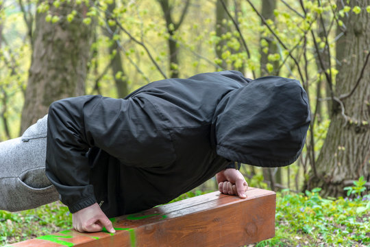 Mężczyzna w kapturze robi pompki na zewnątrz