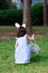 Little toddler girl with bunny ears. Easter egg hunt. - 337056326