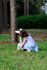 Little toddler girl with bunny ears. Easter egg hunt. - 337056355