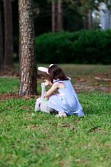 Little toddler girl with bunny ears. Easter egg hunt. - 337056384