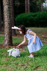 Little toddler girl with bunny ears and surgical face mask hunting for Easter eggs during coronavirus quarantine - 337056724