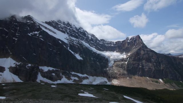 Panning shot of Angel Glacier melting into a lake below at Mt Edith Cavell in Japser during summer from the top of a trail