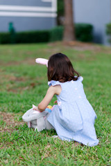 Little toddler girl with bunny ears. Easter egg hunt. - 337057550