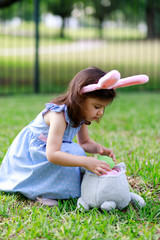 Little toddler girl with bunny ears. Easter egg hunt. - 337057732