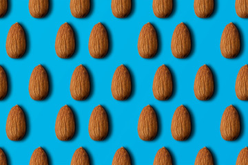 Seamless pattern of almonds on a blue background. top view.