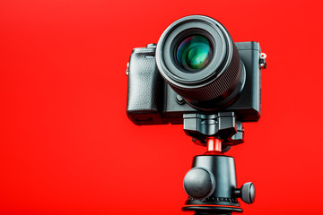 Professional camera on a tripod, on a red background. Record videos and photos for your blog,...