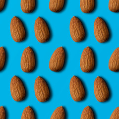 Seamless pattern of almonds on a blue background. top view.