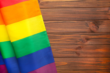 Rainbow LGBT flag on brown wooden background with copy space